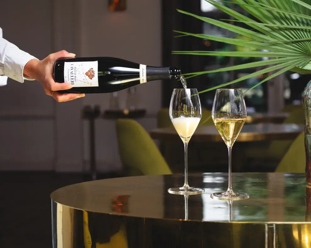 Una mano sirviendo copas de espumante.