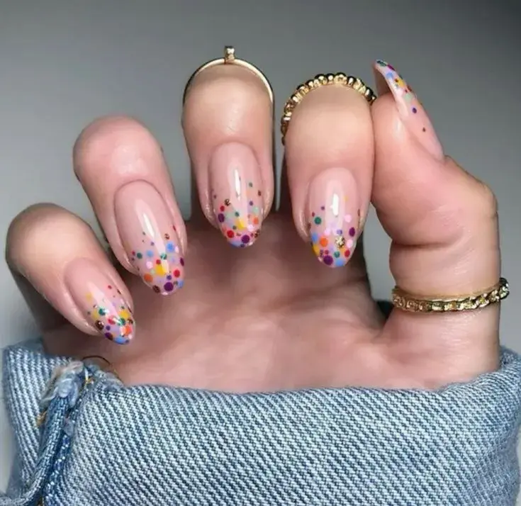 Confetti degradado: los puntos se concentran en la punta o en la raíz de la uña, creando un efecto de transición muy moderno.