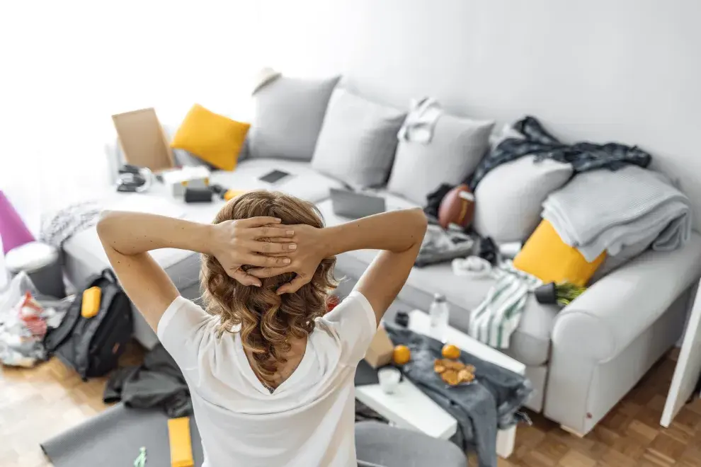 Foto de mujer en su hogar desordenado.
