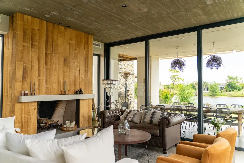 El revestimiento de la chimenea suma aún más calidez a este living con vista al exterior y, más allá, a la laguna.