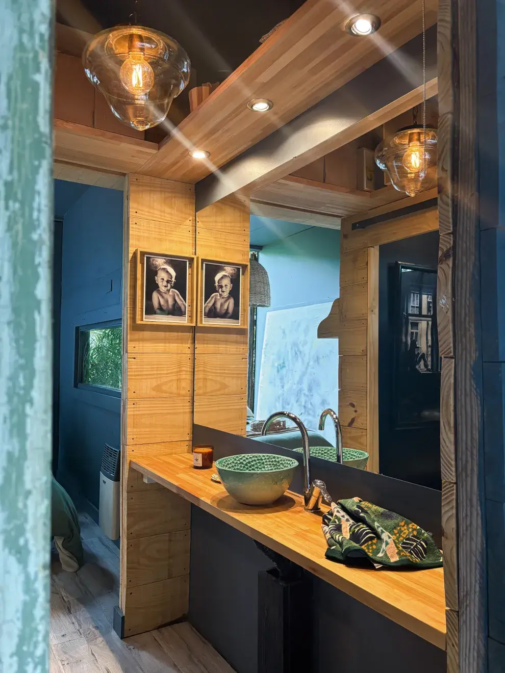 madera y minimalismo son las claves del baño, que se completa con un espejo xl que agranda el espacio, fotos familiares y una bacha artesanal de cerámica.