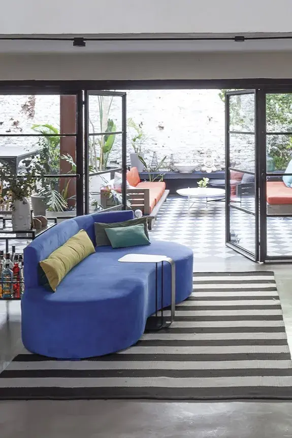 En una obra de Sol Larrosa, sillón azul de segunda mano (Casa The Stock) sobre alfombra rayada de Mihran.