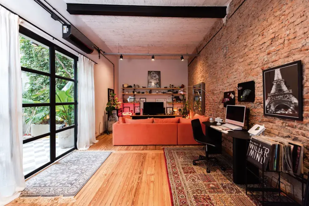 UN MEGASILLÓN PROTAGONISTA EN NARANJA DE @TIENDADEBANQUITOS LE APORTA CALIDEZ A LA VIBRA INDUSTRIAL DEL AMBIENTE. ABAJO, UN SECTOR DONDE COLECCIONA CÁMARAS DE FOTOS Y OBJETOS DE VIAJES. 