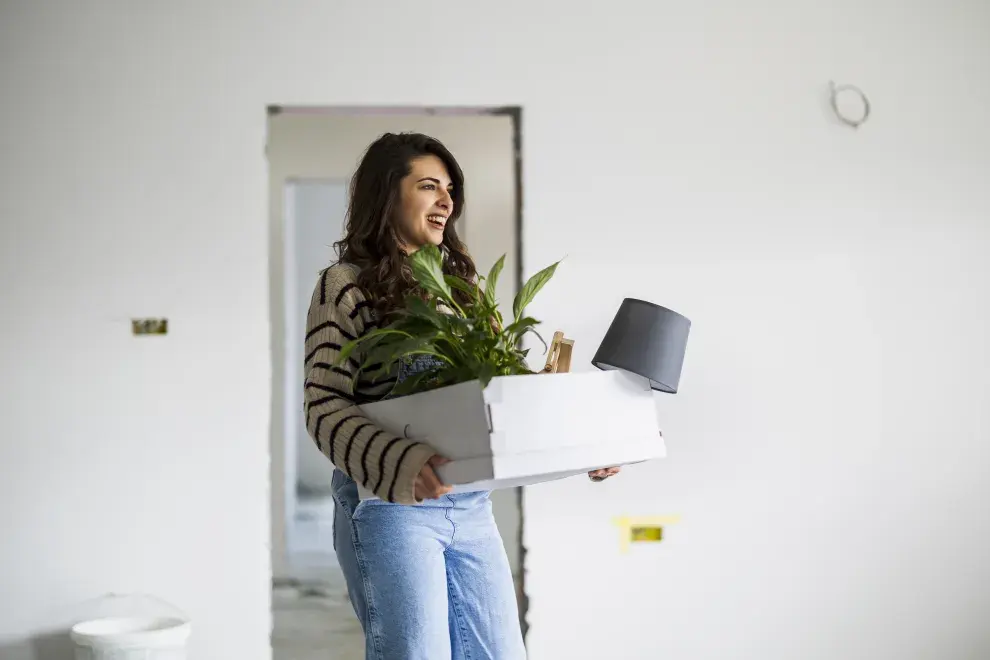 Foto de mujer llegando a su casa con una planta.
