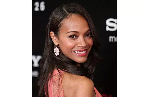Con el pelo suelto y raya al costado, Zoe Saldana usó aros en rosa, en composé con el vestido