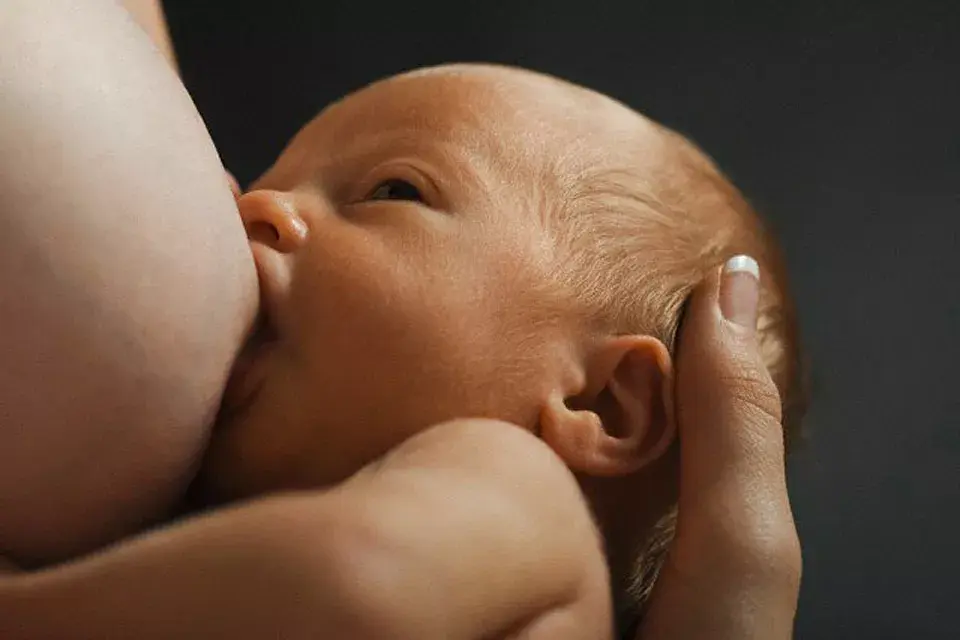 Un bebé mira a su mamá mientras toma la teta