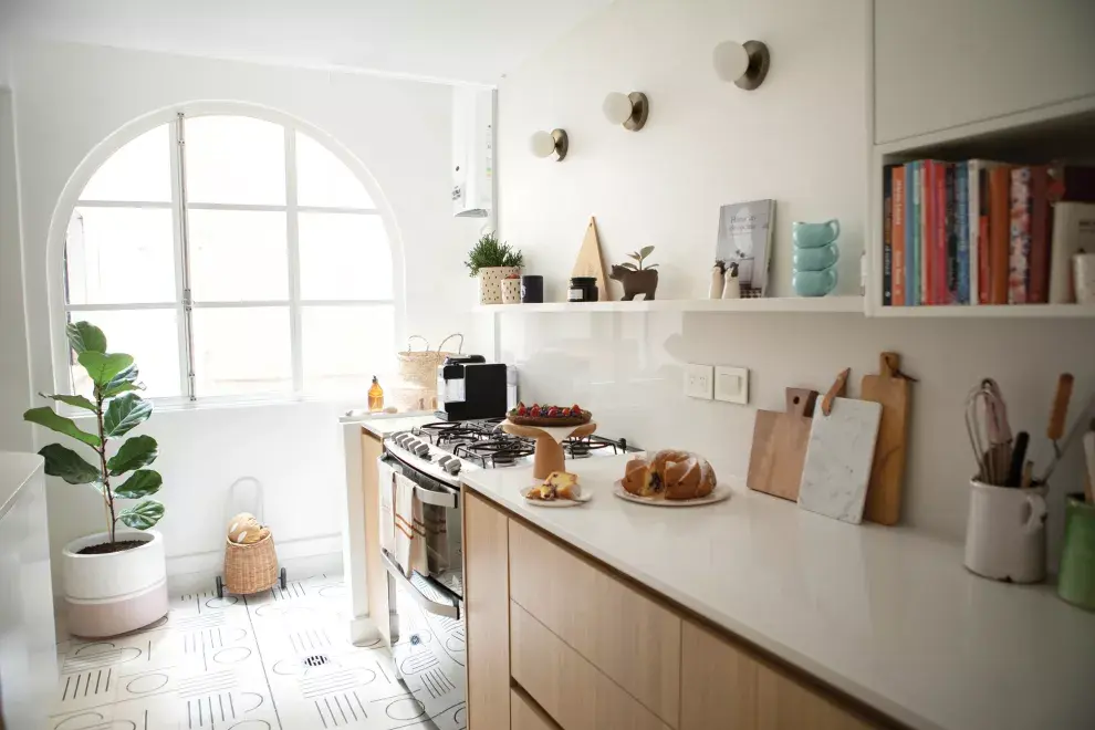 Sobre la mesada, tablitas de madera (Lapacho) y mármol (Paysana). Arriba, libros de cocina, vajilla y plantitas, porque es muy fan del verde. El ficus (Urban Pots) se roba las miradas. 