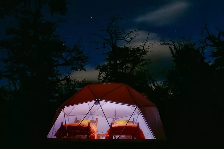 El gran ventanal permite observar el cielo en una noche estrellada en Adventure Domes Patagonia frente al Glaciar Perito Moreno