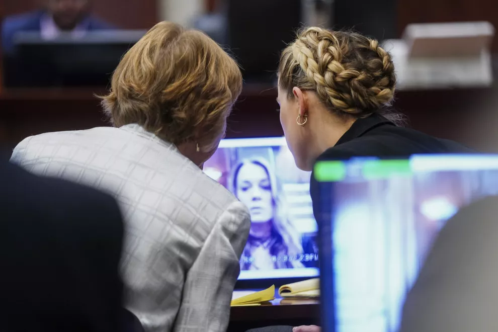 La actriz Amber Heard, derecha, y la abogada Elaine Bredehoft, miran el testimonio por video de la antigua asistente personal de Heard.
(Shawn Thew/Pool Photo via AP)