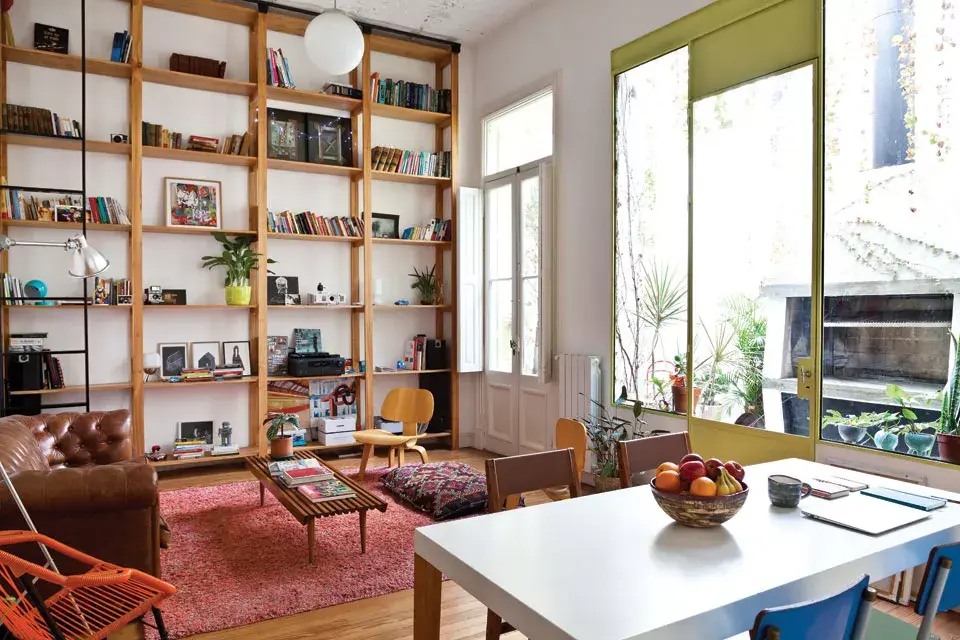 En el sector social, la biblioteca de madera es protagonista. Se destacan también un sillón Chesterfield restaurado, una mesa de comedor (Manifesto) y un vajillero del Mercado de las Pulgas con copas heredadas. En cuanto a objetos: maceta de cerámica hecha por su mamá, lámpara (Ikea), cuadritos que