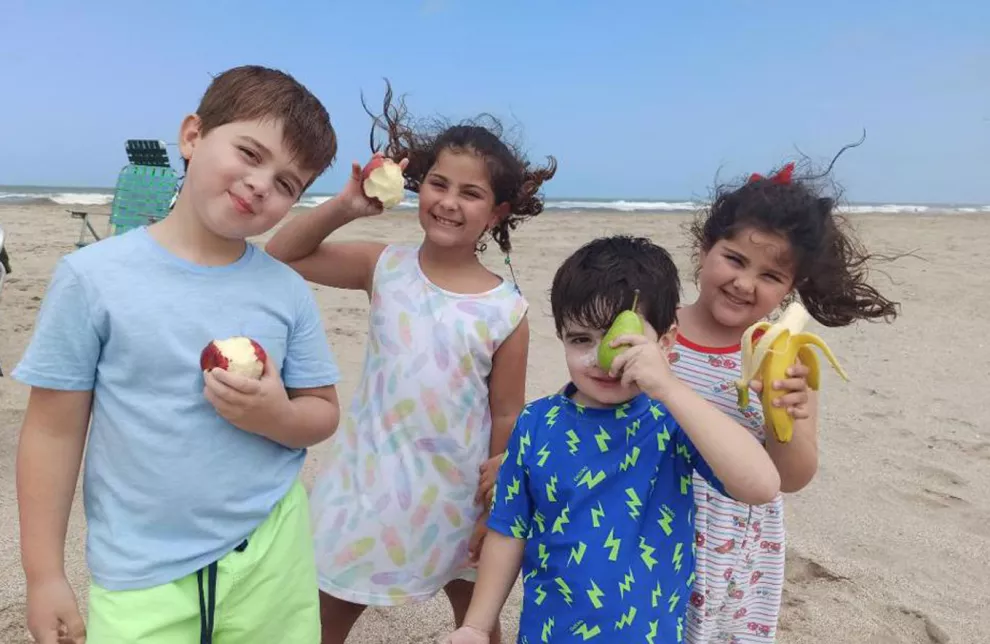 Agustín, Esmeralda, Benjamín y Felicitas disfrutan de una merienda saludable en la playa; la idea es que repliquen esos hábitos en la vuelta al cole
