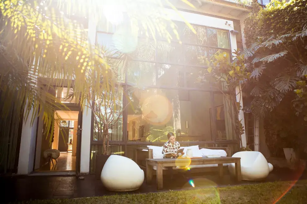 Un enorme panel de vidrio repartido conecta el living con el jardín, donde además hay una pileta muy años 50. En la terraza, Coty y sus muebles de jardín (Laura O).