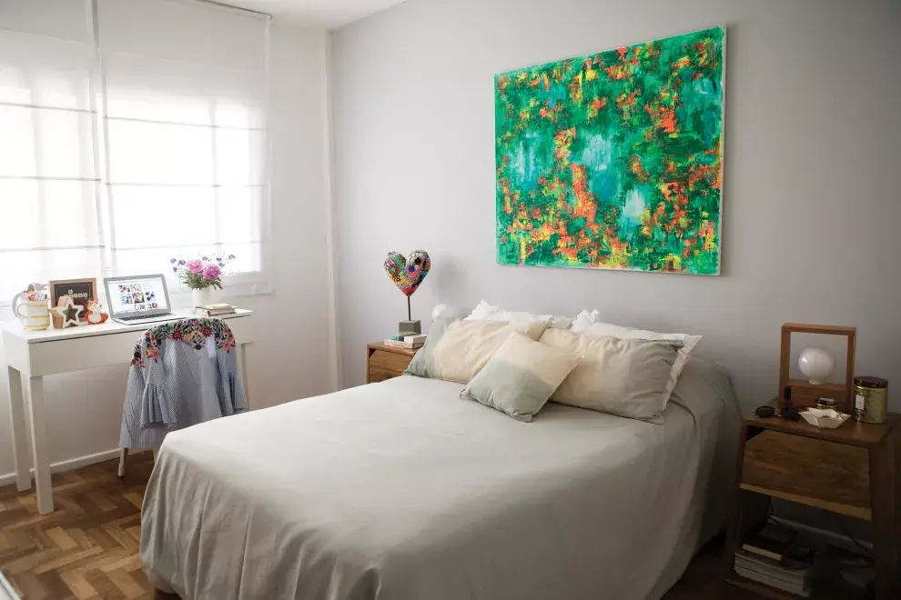 “Sobre esta cama tomé la decisión de dejar la abogacía. Fue en una vuelta de mis vacaciones. Pensé que me la tenía que jugar por el blog”. Optó por una paleta de colores relajantes. El impacto está en el cuadro de Carolina Bianchetti, sobre la cama con acolchado y almohadones (Arredo). Mesas de luz
