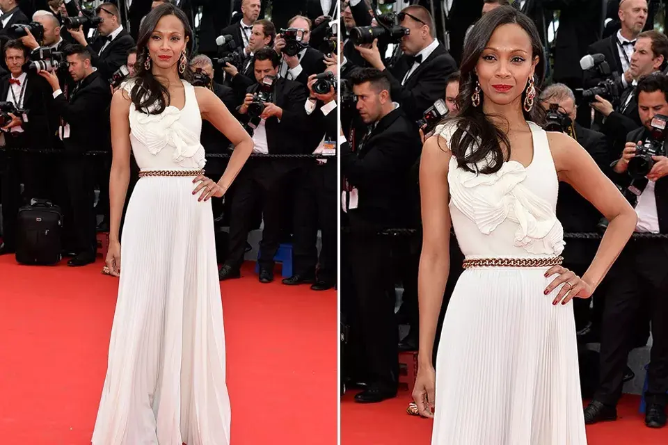 Zoe Saldana es otra de las famosas que optó por dos diseños bien distintos a la hora de atravesar la alfombra roja. En esta oportunidad llevó un vestido blanco con falda y detalles plisados y un importante cinturón de cadena, by Victoria Beckham