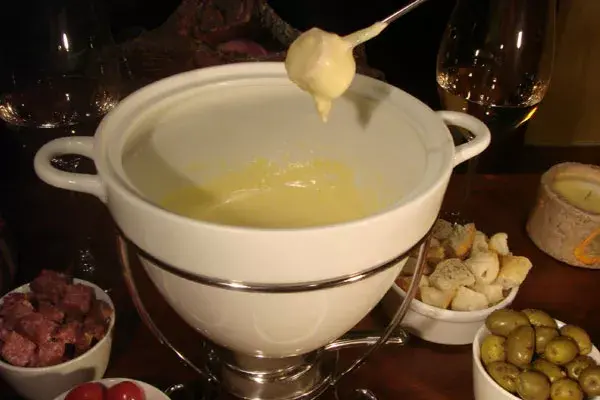 Fondue de queso con salchichas ahumadas, cubitos de salamín picado fino, cubitos de jamón natural, tomates cherry, entre otras cosas