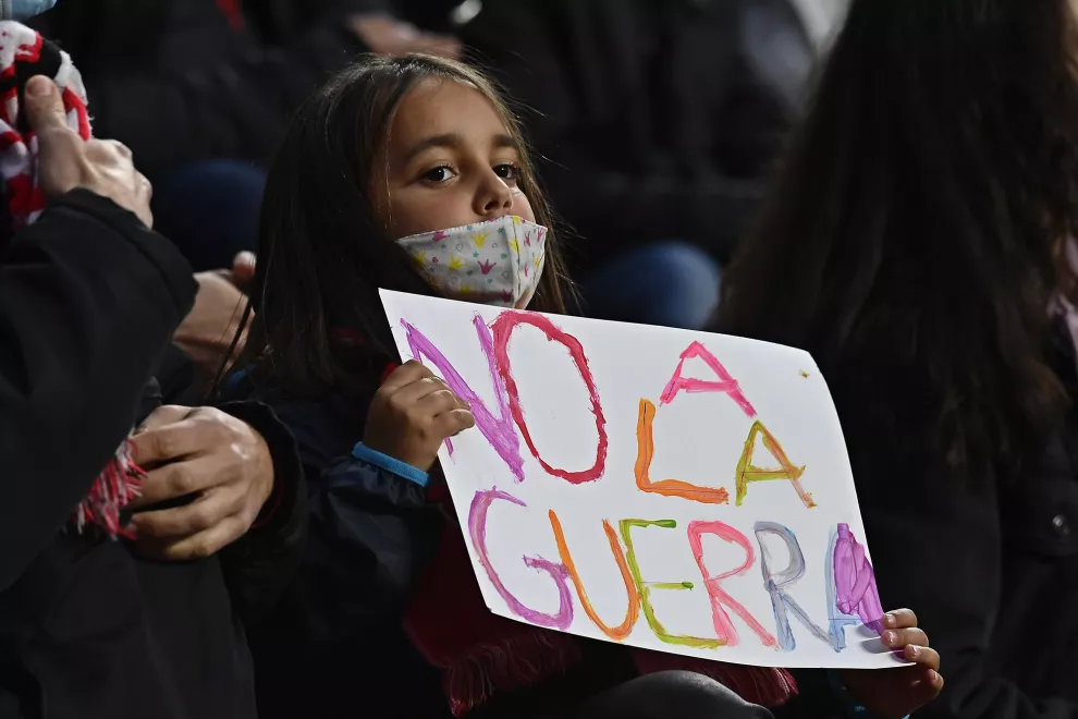 Una niña sostiene un mensaje que dice "No a la guerra" en las gradas antes del inicio del partido entre Rayo Vallecano y el Real Madrid en el estadio de Vallecas en Madrid.