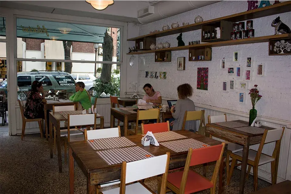 Sillas de colores y mesas de madera para sentarse a comer platos tentadores