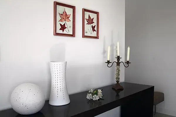 Rincón con un dresoire ($9094, Fontenla), lámparas de cerámica en color crudo ($800 c/u, Línea D Interiorismo), candelabro en hierro y vidrio y dos cuadritos pintados al óleo ($150 c/u, Nana mía) en los tonos de la ambientación