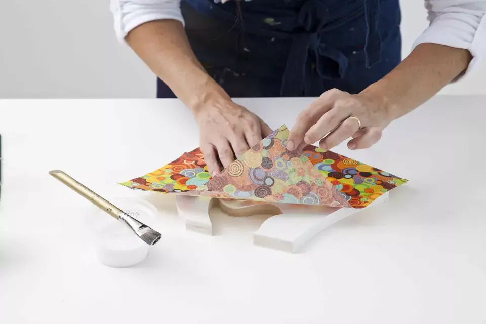 2/ Aplicar barniz mate sobre la madera y la servilleta (poca cantidad), luego apoyar la servilleta presionando suavemente. Con una pinceleta, extender el barniz desde el centro hacia los laterales para quitar cualquier burbuja o exceso de barniz