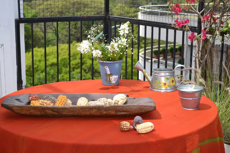 Se armó una mesa con un mantel rústico en un naranja fuerte que da lugar a un puñado de detalles de campo, como el cuenco de madera antiguo (El Postigo Muebles), la maceta artesanal ($80) y la regadera de zinc con girasoles pintados a mano ($100, todo Nana mía)