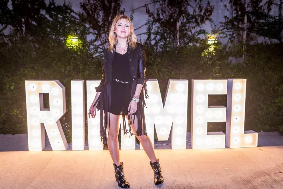 Stephanie Demner, con una campera con flecos, vestido negro y botas con estrellas en la presentación de la nueva colección de Rimmel