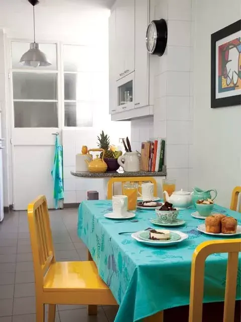 En la mesada: tarro de cerámica con tapa de lechuza, una pava amarilla y un bol violeta (Bartolomea, $307, $793 y $396) y una jarra de cerámica para cucharones (Ketha, $420). La mesa está vestida con un mantel (Salmón Tienda, $750).