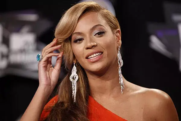 Beyonce, con un peinado elaborado, con raya al costado y ondas, optó por usar aros largos con brillo