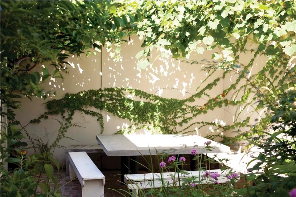 La mesa de concreto de lados irregulares, con bancos del mismo material, le dan al patio un toque moderno