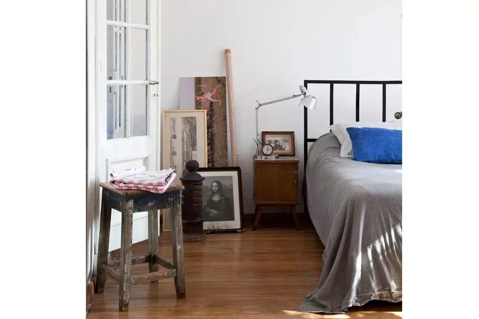 Para la pared de la cabecera eligieron un vinilo que emula el respaldo. Los almohadones en pana azul son de Ketha ($360) y la lámpara sobre la mesa de luz es de Iluminación Agüero ($800). La banqueta la pagaron $400 en Lo de Pili, en el Mercado de Pulgas