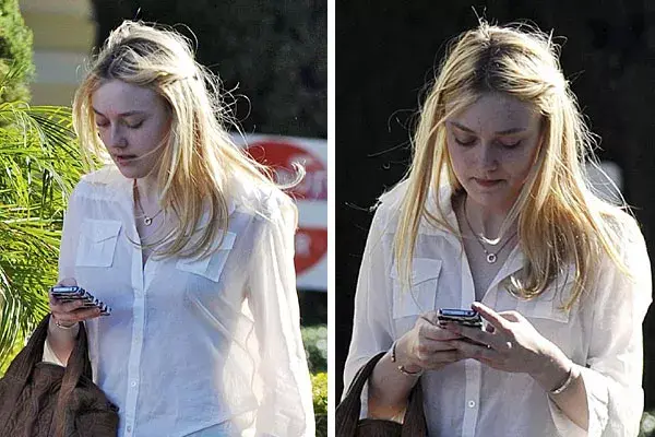 Despreocuada, Dakota Fanning camina por la calle mirando su teléfono sin preocuparle su look desprolijo