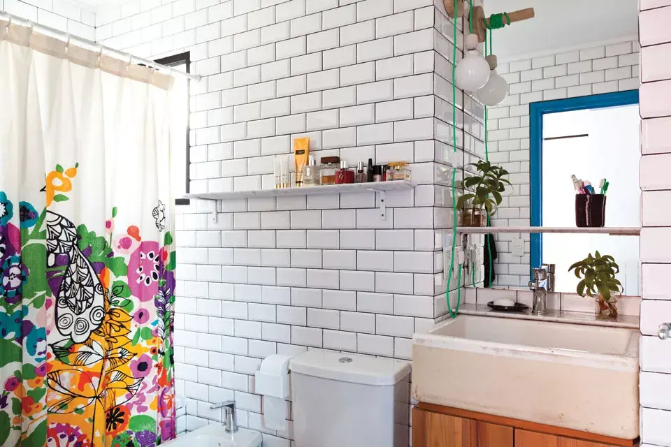 Explosión de color para esta cortina de baño de Urban Outfitters. El resto, todo blanco: cerámicas esmaltadas, estantes y una bacha de demolición.