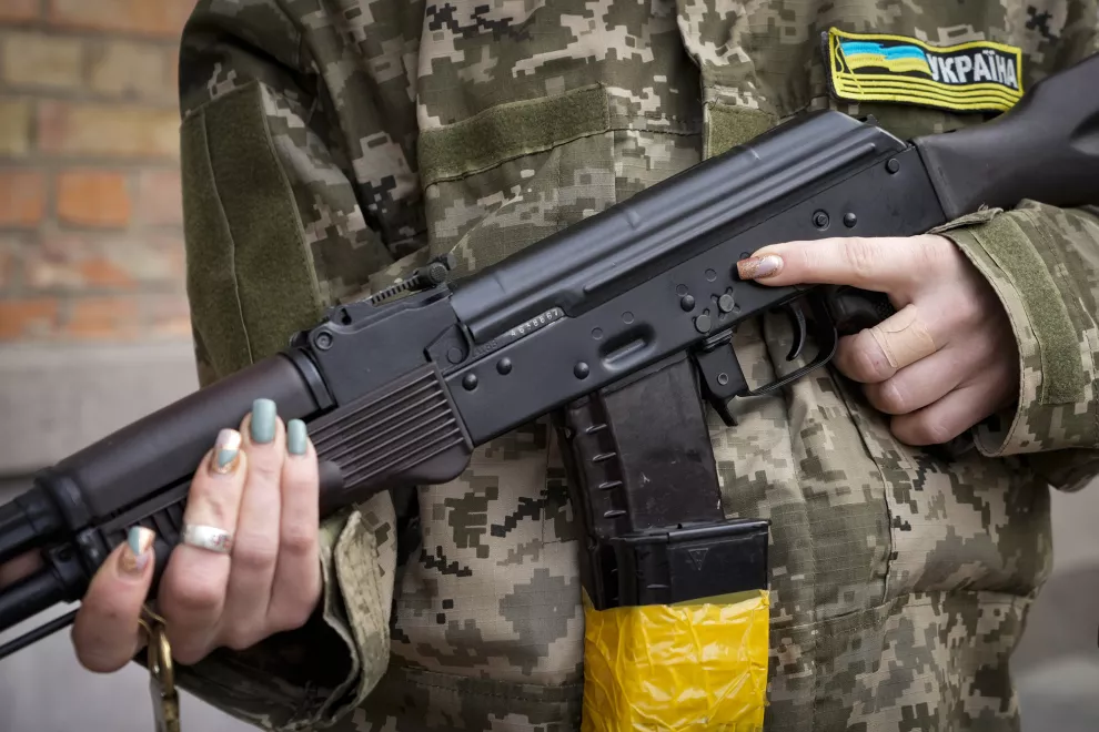 Una mujer armada de defensa civil sostiene un rifle de asalto Kalashnikov mientras patrulla una calle vacía debido al toque de queda en Kiev.