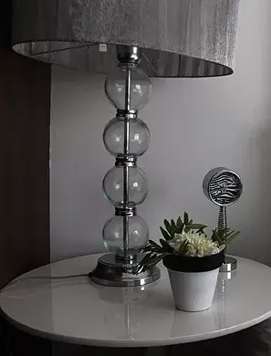 Sobre la mesa de luz Ditry ($4714, Fontenla), lámpara con pie de metal y globitos de vidrio, reloj metálico con diseño de cebra ($59.90, Magneto). Maceta en blanco y negro ($20, Nana mía)