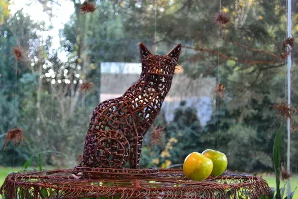 En primer plano, un gato esculpido en hierro se lleva todas las miradas