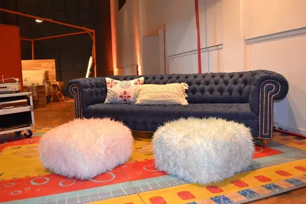 Un imponente sillón capitoné en azul se roba todas las miradas en el espacio de Diamante Sillones. A sus pies, dos pufs peluditos suman diseño