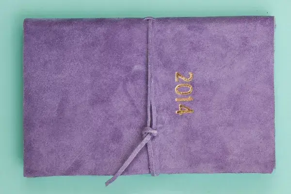 De gamuza violeta con grabado en color oro (Muchos Mundos, $170)