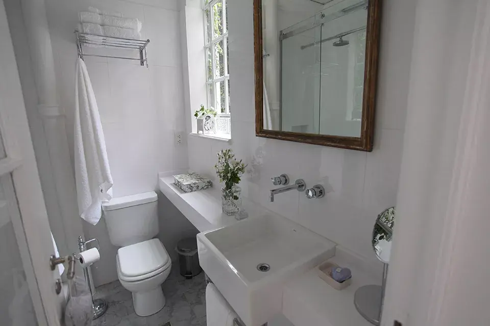 El baño combina lo antiguo con lo moderno: se mantuvieron las aberturas, el piso, las molduras y la columna de desagüe que se dejó a la vista. Aprovechando al máximo cada espacio, se colocó sobre el inodoro un rack para toallas