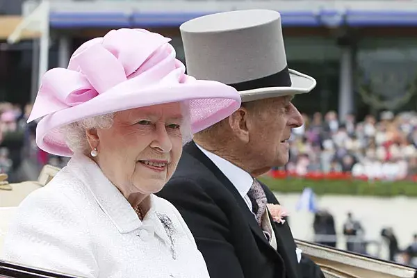 Sobrios, la reina de Inglaterra, con una capelina rosa, y su marido, el duque de Edimburgo