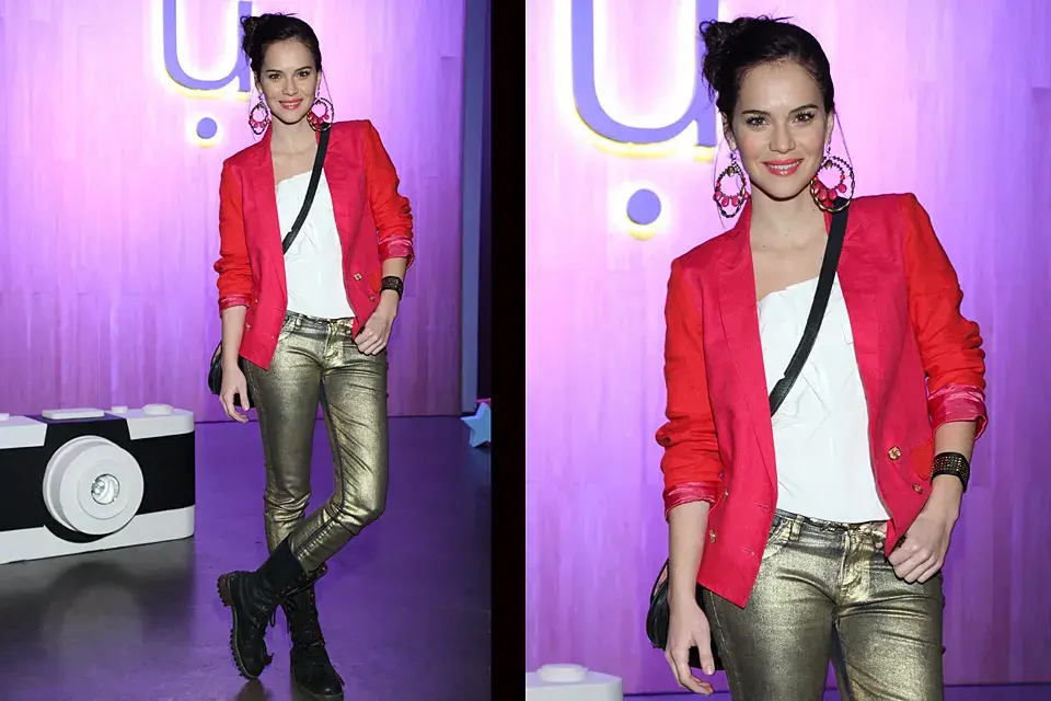 Luz Cipriota, bien trendy, se puso pantalones dorados con borcegos y blazer bicolor en fucsia y rojo para sentarse en la primera fila de UMA ¿Los accesorios? Mega aros, pulsera con tachas y bandolera