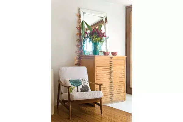 Ella es muy ordenada y encontró en este mueble guardaplanos una alternativa perfecta para el guardado de pequeños objetos. El toque de color lo da este arreglo de penacho fucsia, sorgo y hojas de strelitzia en un florero turquesa de vidrio ($150 y $220, Tete Castells - Delivery de flores)