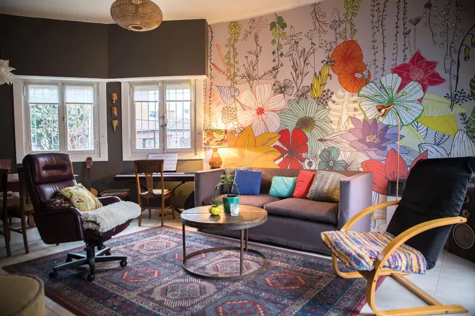 El empapelado “Plantas” (Enamorada del Muro) le da el marco perfecto a este living con sillón de dos cuerpos (Della Casa), mesa ratona comprada en Tigre y puf redondo de arpillera (Falabella).