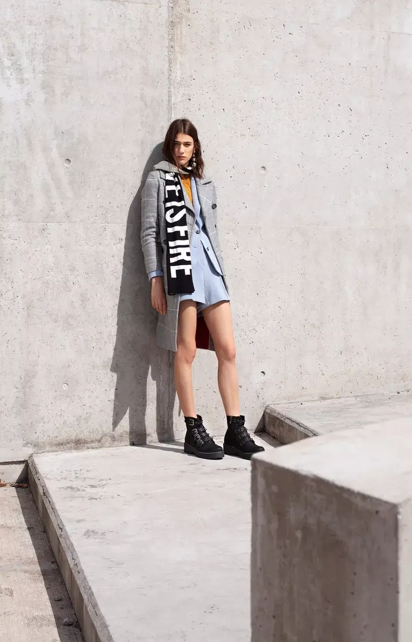 Tapado (Vitamina, $14.000), traje de saco y short (Tommy Hilfiger, $4762 y $2680), suéter (Complot, $1490), aros (Luna Garzón, $1100), bufanda con inscripción (Kosiuko, $2800), borcegos (Viamo, $2950)