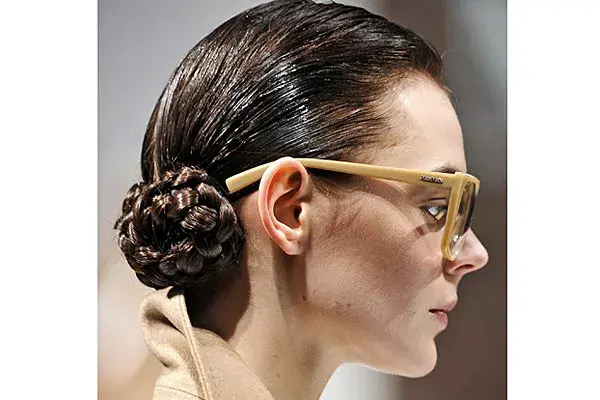 Armá una raya al costado, luego dos colitas bien bajas. Colocá gel en la parte superior de la cabeza. Trenzá cada colita y recogelas en forma circular. Podés usar un poco de spray sobre las trenzas para evitar el frizz. Max Mara.