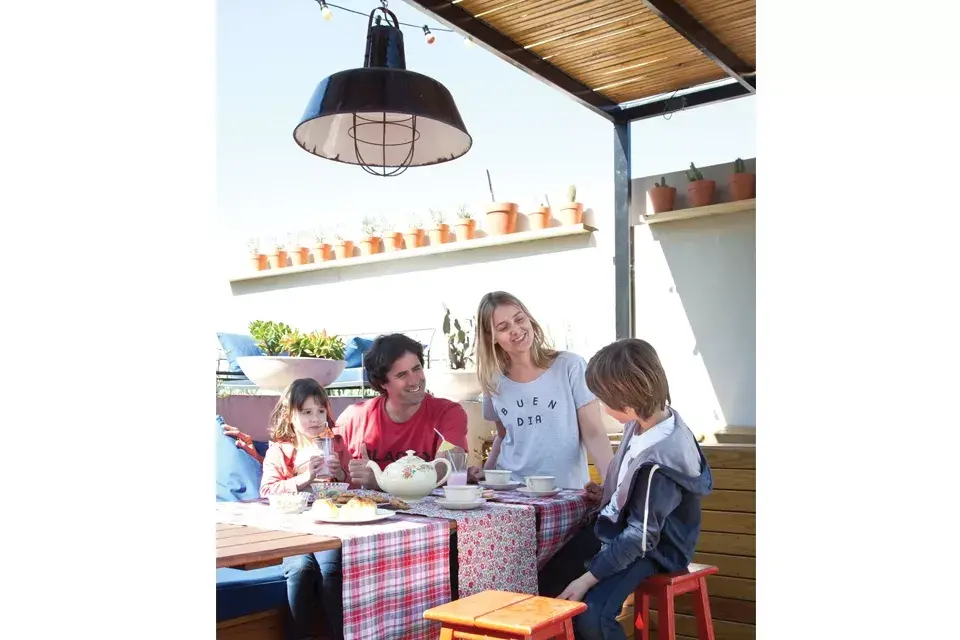 La familia, a pleno, disfruta de tomar la merienda en el patio. La mesa larga ($5999 aprox) y las banquetas son de Easy
