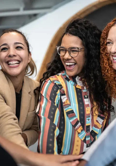 mujeres juntan manos en el trabajo