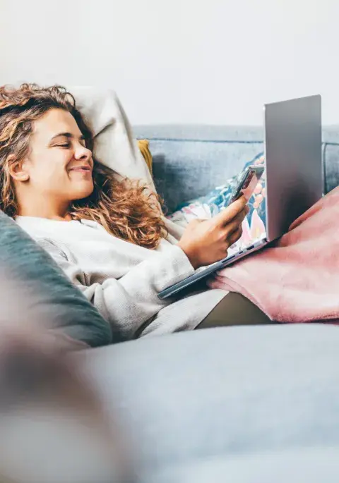 mujer joven en casa con tecnología tapada por el frio