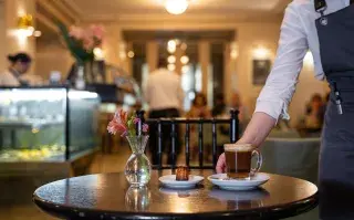 Una de las mozas sirve una mesa en la confitería Pasaje de los Carruajes en el Teatro Colón.