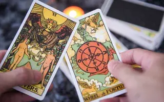 Dos cartas de tarot sostenidas por una mano.