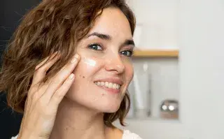 Mujer colocándose crema hidratante.