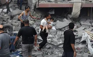 Un palestino lleva a un niño rescatado de la casa de la familia Tattari, que fue destruida en un ataque aéreo israelí en la ciudad de Gaza el 9 de octubre de 2023. Entre los muertos hay 4 argentinos; al menos otros 4 están desaparecidos.